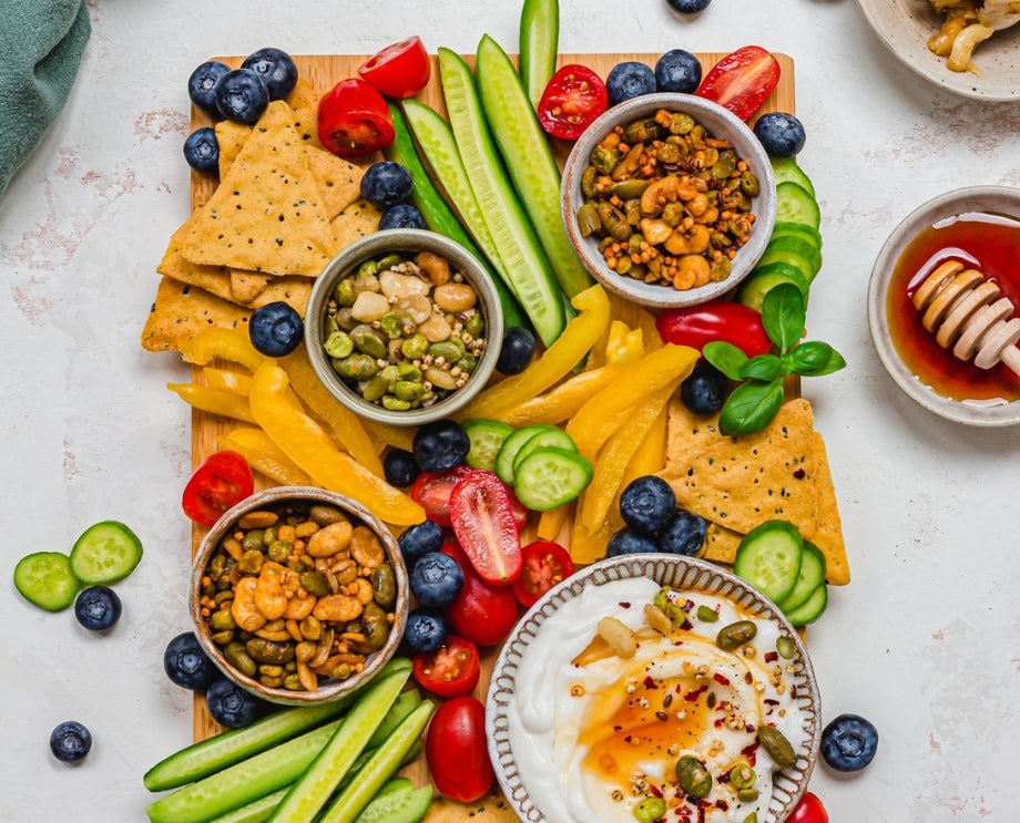 Sharing board with vegetables, tortilla chips, garlic whipped feta, and Nature's Heart Crunch