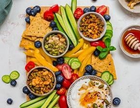 Sharing board with vegetables, tortilla chips, garlic whipped feta, and Nature's Heart Crunch