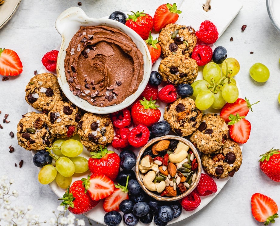 Sharing board with fruit, trail mix cookies, fruit and nut mix, and chocolate hummus