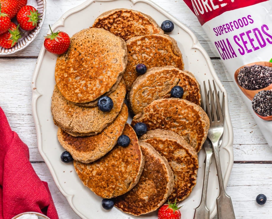 A platter of vegan pancakes with a sprinkling of blueberries and strawberries